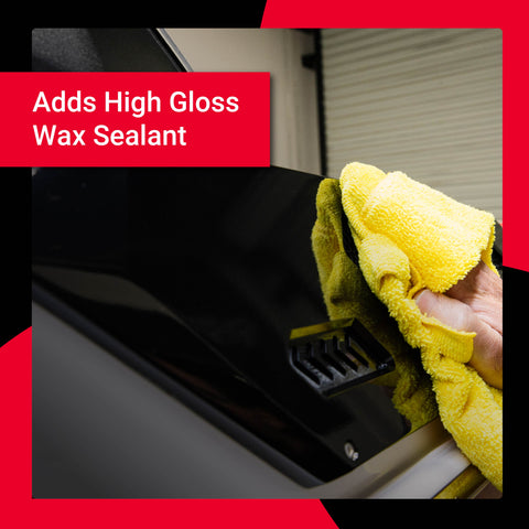 A person applying a high gloss wax sealant to a vehicle's surface with a yellow microfiber cloth.