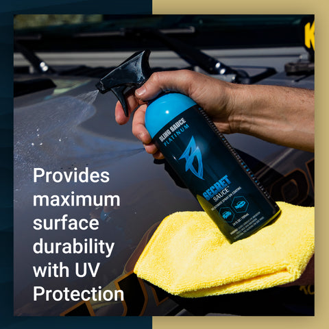 Hand holding a spray bottle of Secret Sauce while cleaning a vehicle surface with a yellow microfiber cloth, showcasing UV protection.