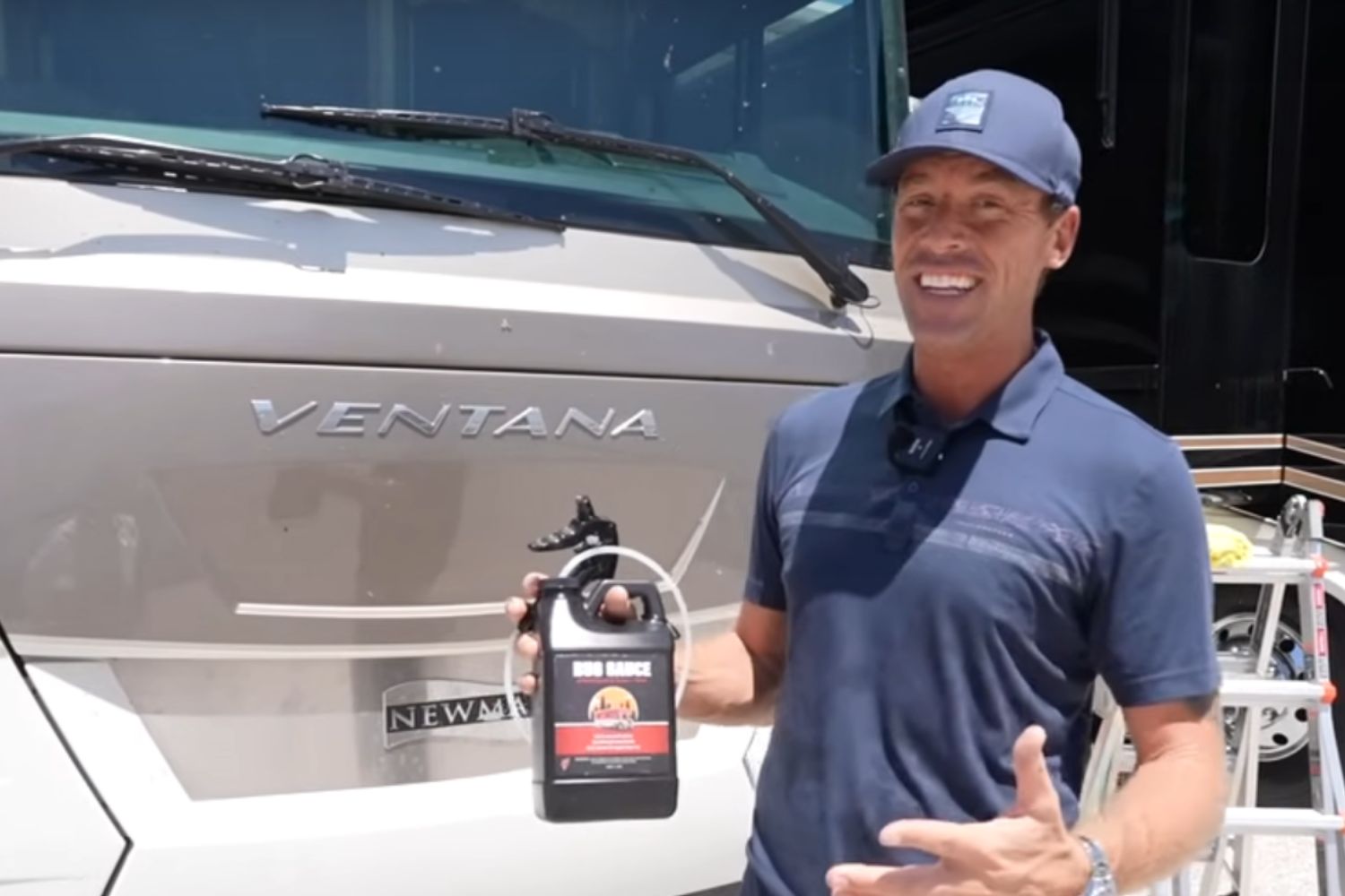 Man holding a black and red vehicle cleaning solution bottle in front of a boat with "VENTANA" logo, showcasing premium de...