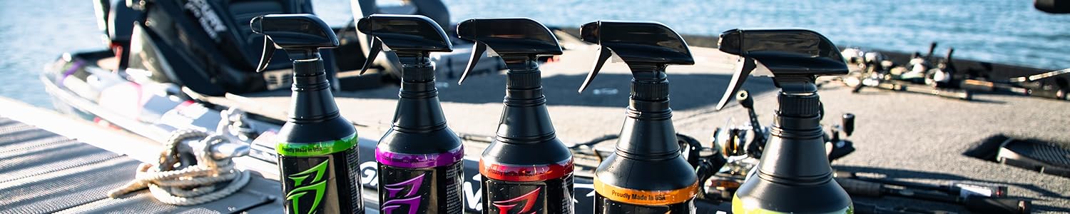 Set of five black spray bottles with colored labels (green, purple, red, orange, yellow) on a boat deck, used for premium ...
