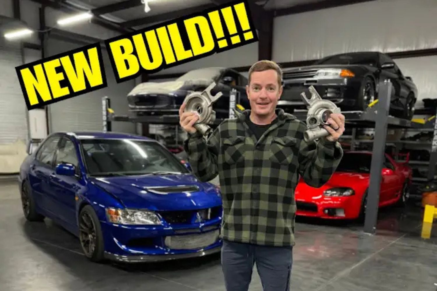 Man holding turbochargers in a garage with blue, red, and black cars; bold yellow "NEW BUILDI!!!" text overlay.